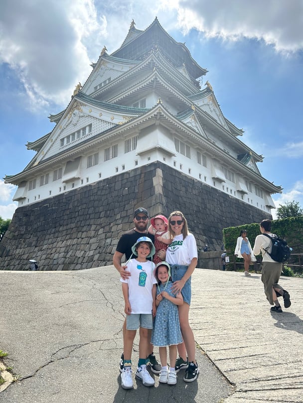 family taking picture in front of the Osaka Castle in Japan