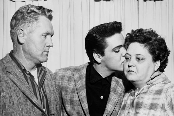 Elvis gives his mother Gladys a kiss while his father Vernon watches on.