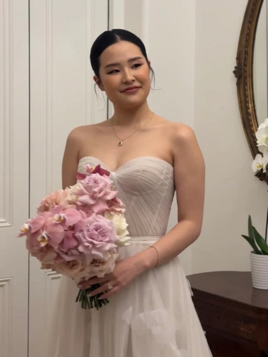 Woman wearing wedding gown and holding a bouquet. 