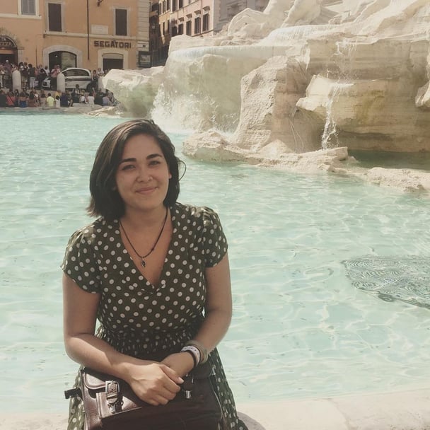 Hannah Kobayashi sitting in front of the trevi fountain in a polka dot dress.