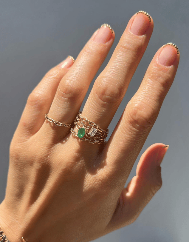 French manicure with small gold jewels on the tips of nails, shaped in a nail crown design