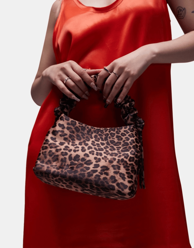 Woman in a red dress holding a leopard print handbag.