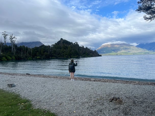 A woman standing by the lake at Bob's Cove with the mountain background. 