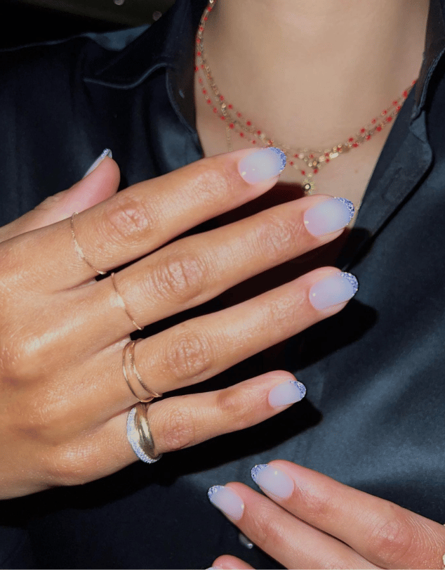 Milky blue manicure with blue jewels on the tips of nails, shaped in a nail crown design