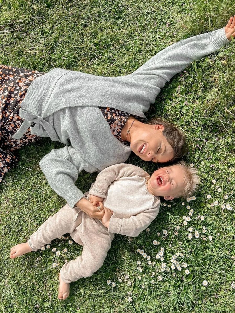 Louise Thompson laughing on the grass with her son, Leo. 