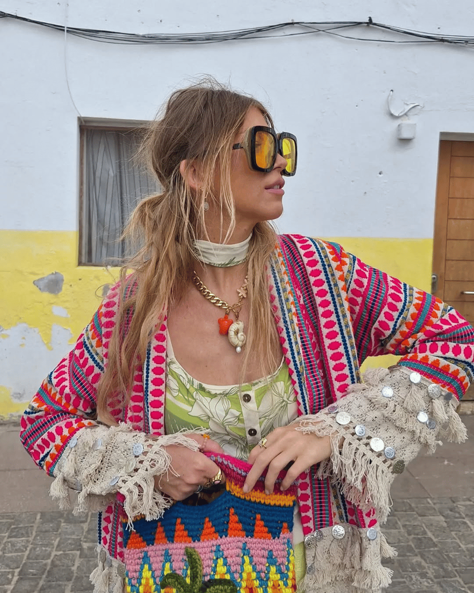 Woman wearing a colourful jacket and charm necklace. 