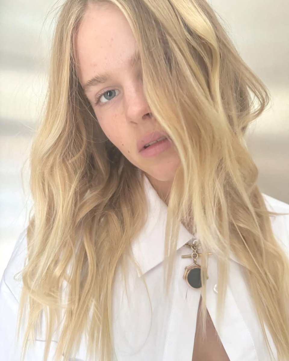 A picture of a woman with long, blonde hair in a white shirt.