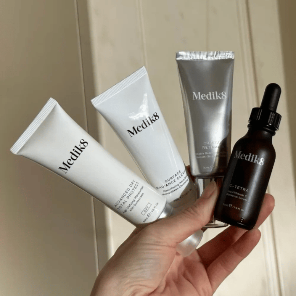 Woman's hand holding Medik8 skincare products.