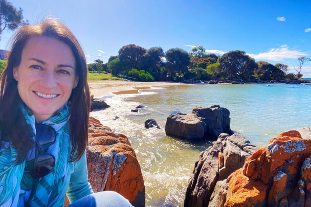 Alice spending time outdoors on a beach with clear turquoise water.