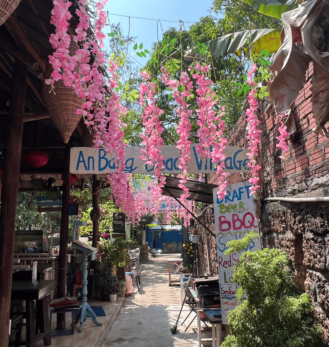 The entrance to An Bang Beach Village: colourful pink flowers overflow off vintage buildings.