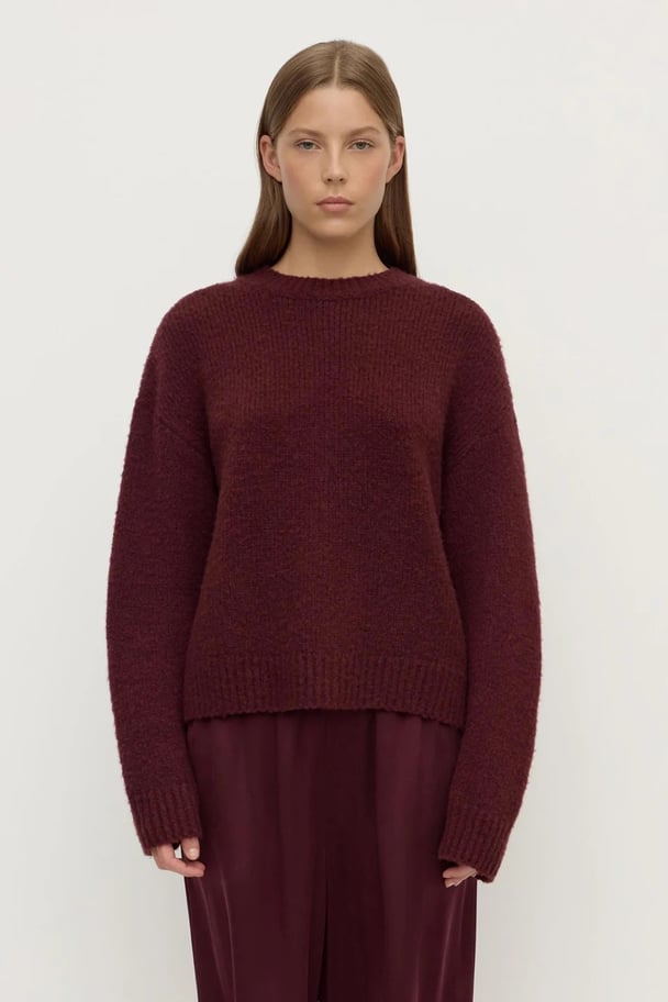 Woman wearing a merlot-colored, slightly cropped alpaca-wool blend crew neck sweater.