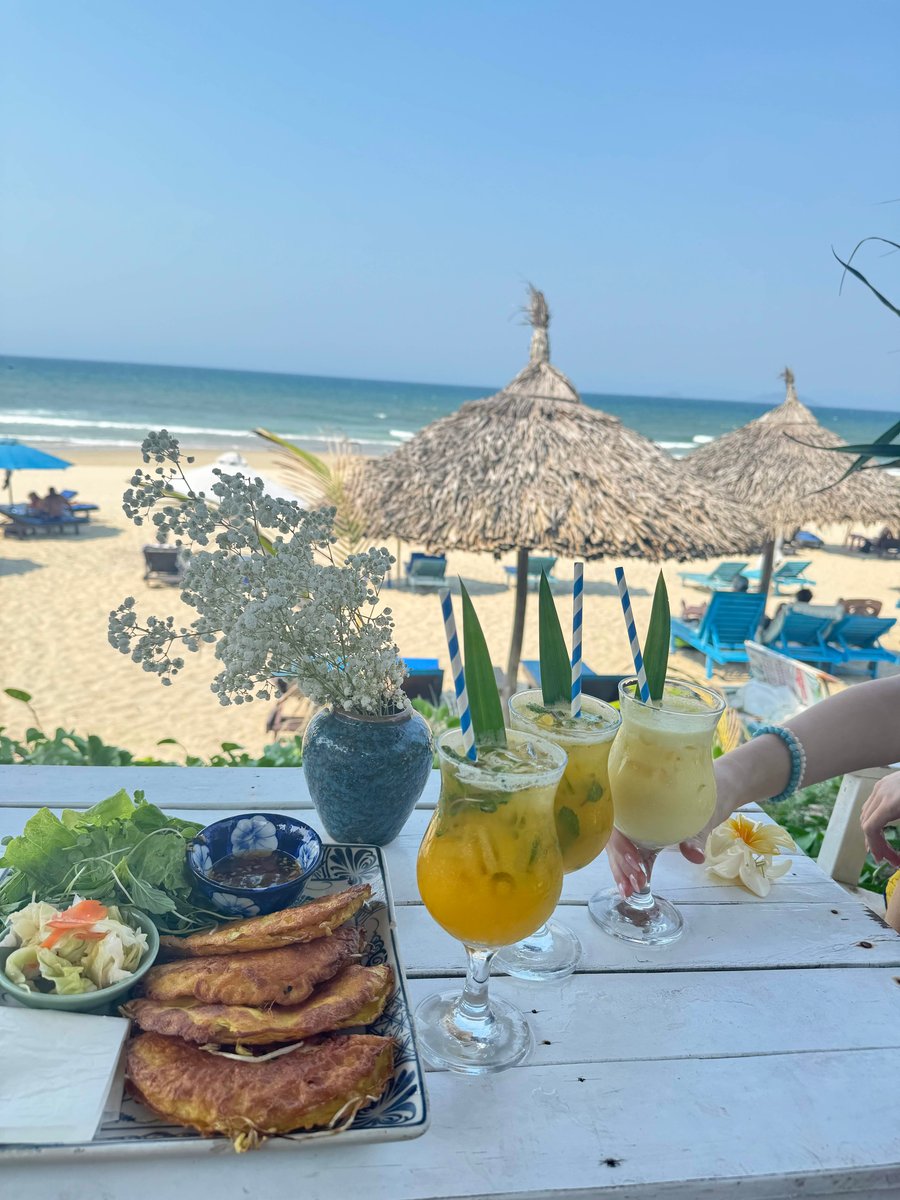 Vietnamese food and colourful cocktails plated on a table on the beach.