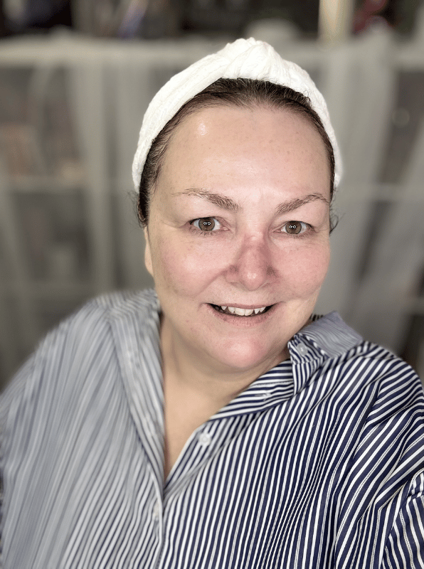 A woman with clear, glowy skin smiles at camera.