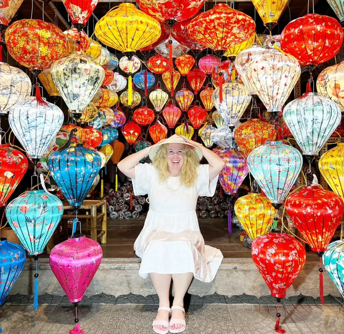 Woman sits in between lots of colourful lanterns in Hoi An.