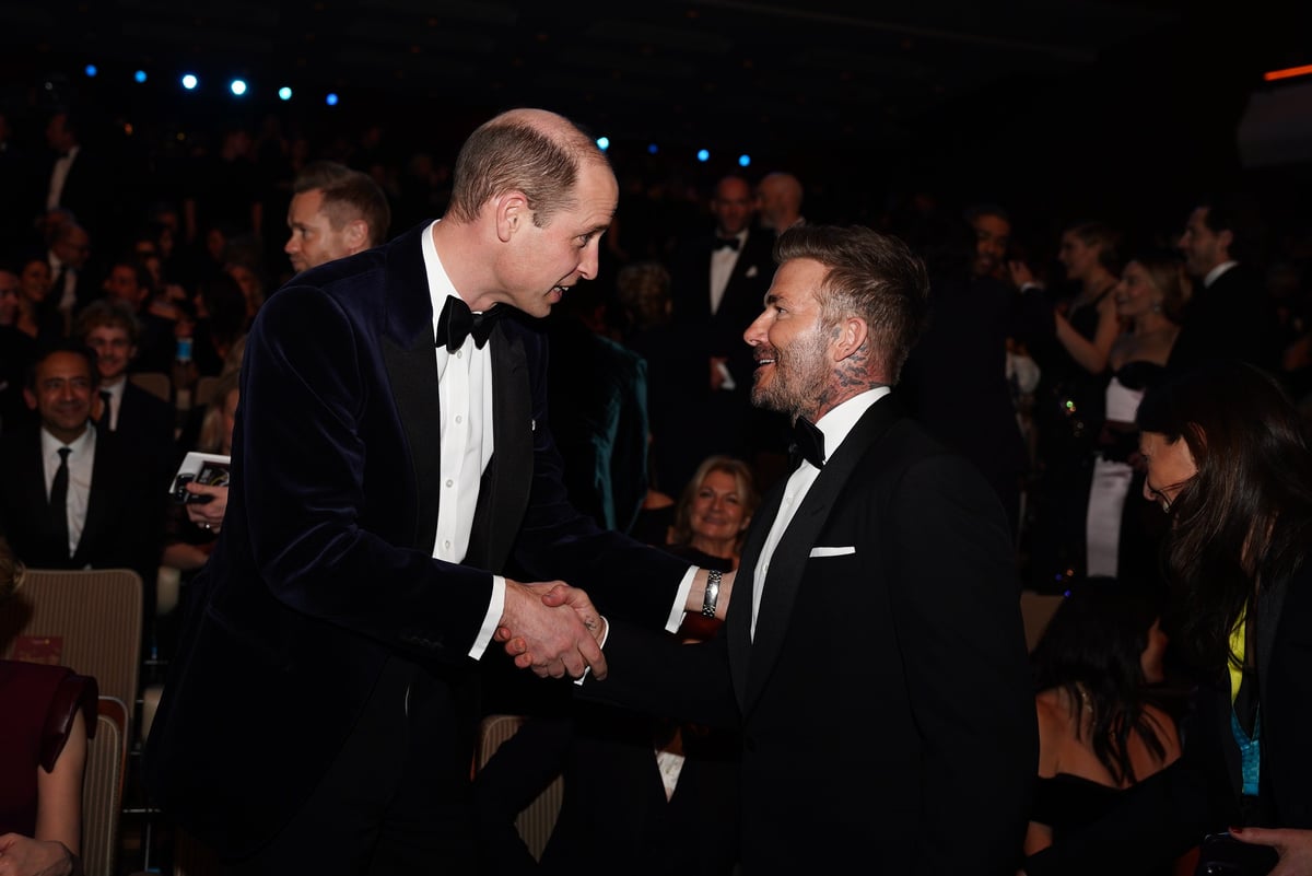 Prince William and David Beckham shaking hands at a black tie event.