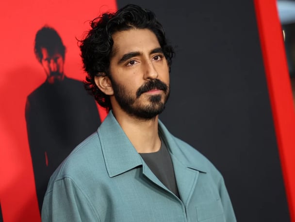 Dev Patel attends the Los Angeles premiere of Universal Pictures' Monkey Man, standing in front of a poster for the movie.