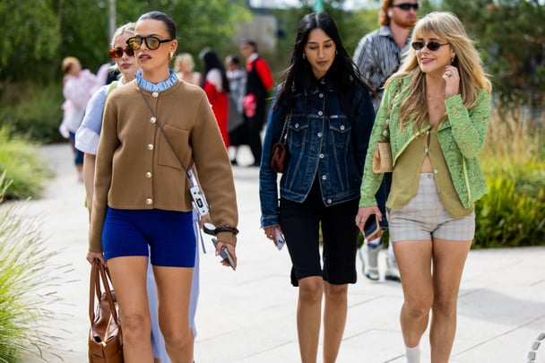 Three women attend fashion week in Copenhagen in stylish fitted outfits.