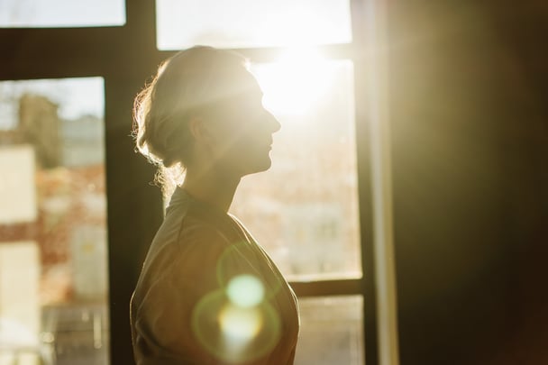 Woman face hidden by soft yellow light.