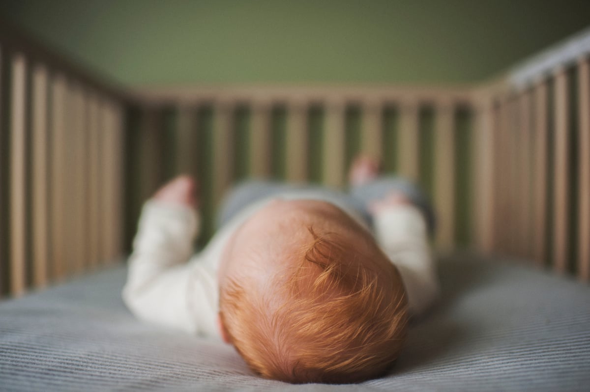 baby sleeping on back in cot