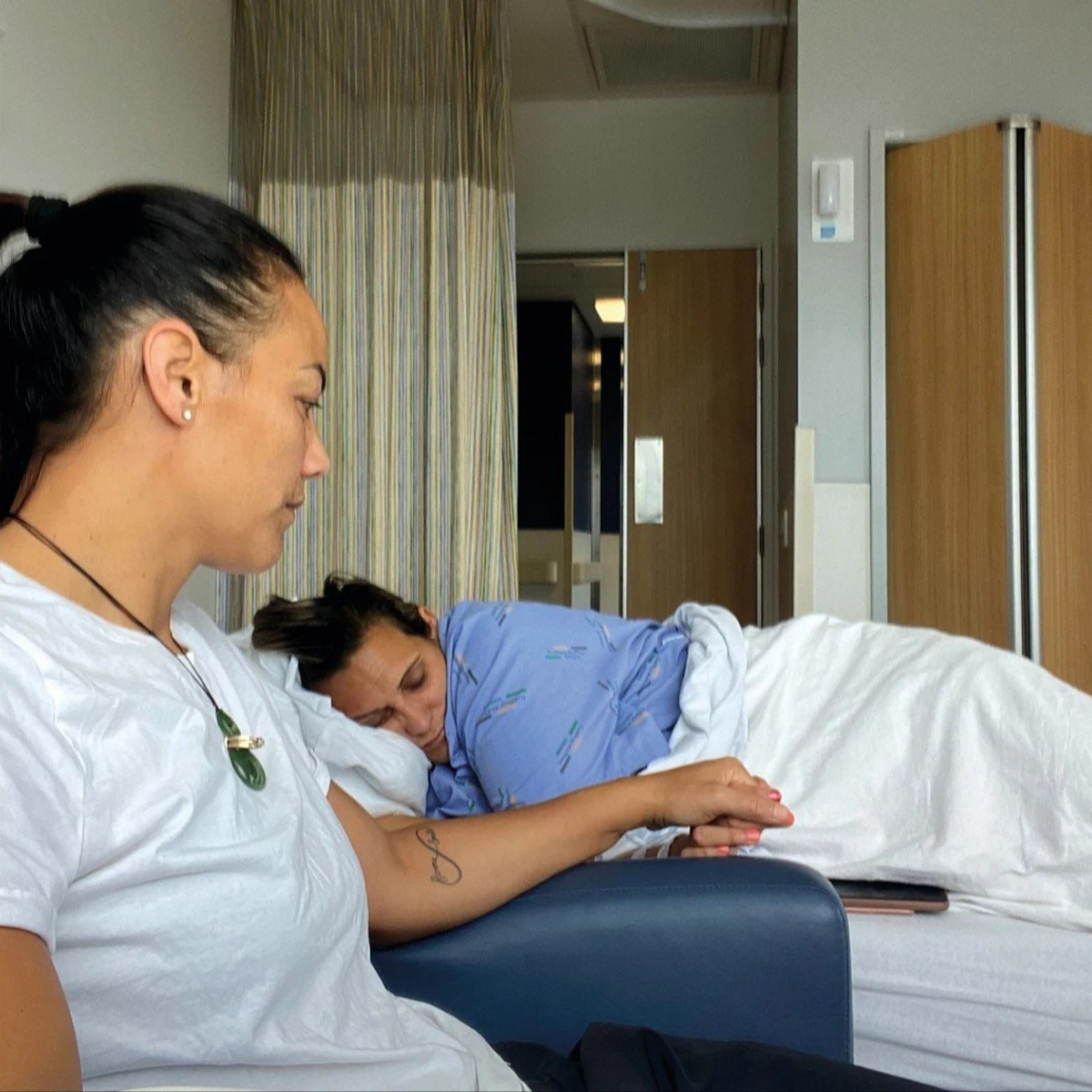 Honey sitting with her wife in the hospital bed.