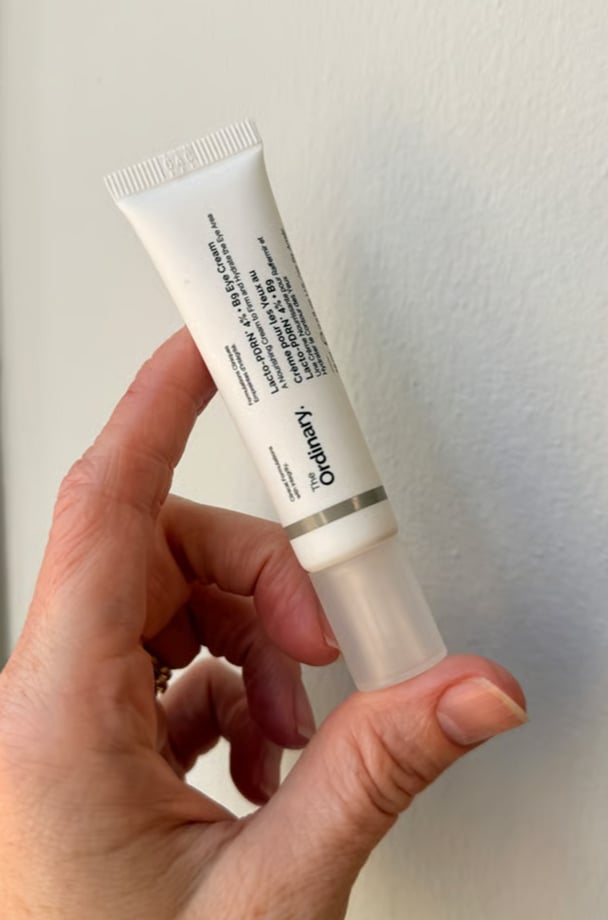 A hand holding The Ordinary's new Lacto-PDRN 4% + Bg Eye Cream.