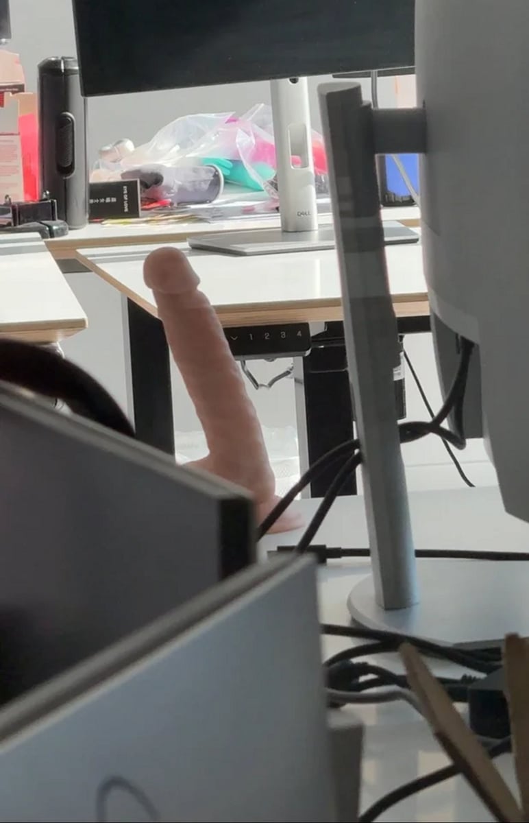 A dildo sitting on a desk, in an office environment.