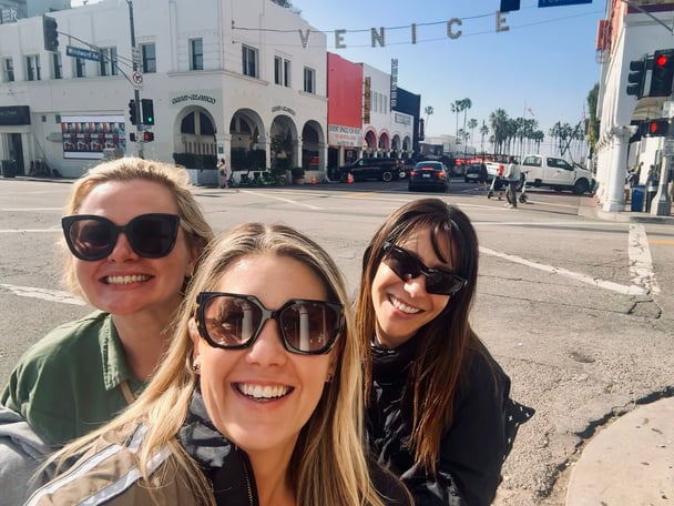 Selfie of Sasha and two friends on the road in Venice underneath a 'Venice' sign.
