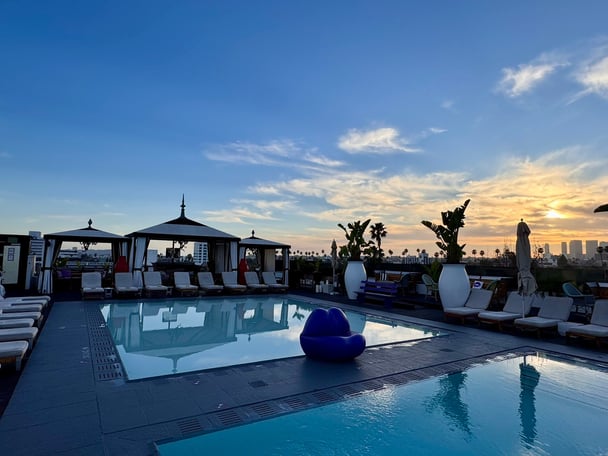 A large hotel pool and cabanas at sunset.