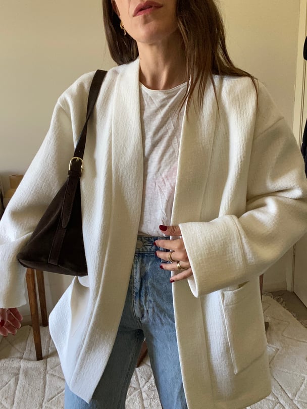 Author wears a white tailored jacket and blue jeans.