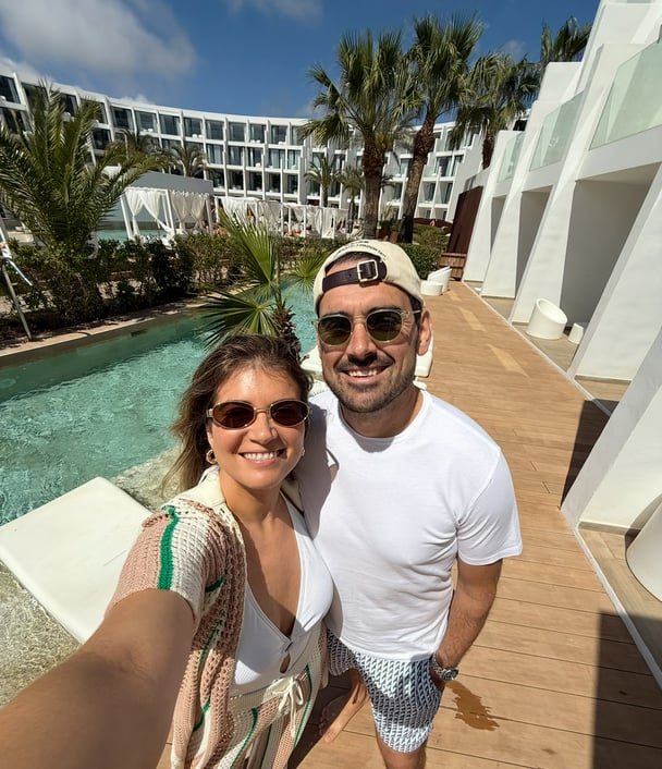 Paige and her partner by the pool at a hotel during their trip.