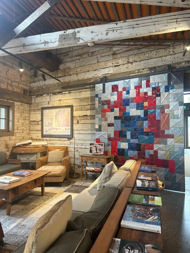 A communal lounge room featuring couches, a wooden coffee table and a handmade mosiac sliding door in shades of blue and red.