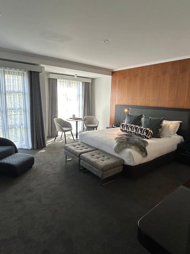 Hotel room at the Sofitel Queenstown, with a double bed and grey lounge. 