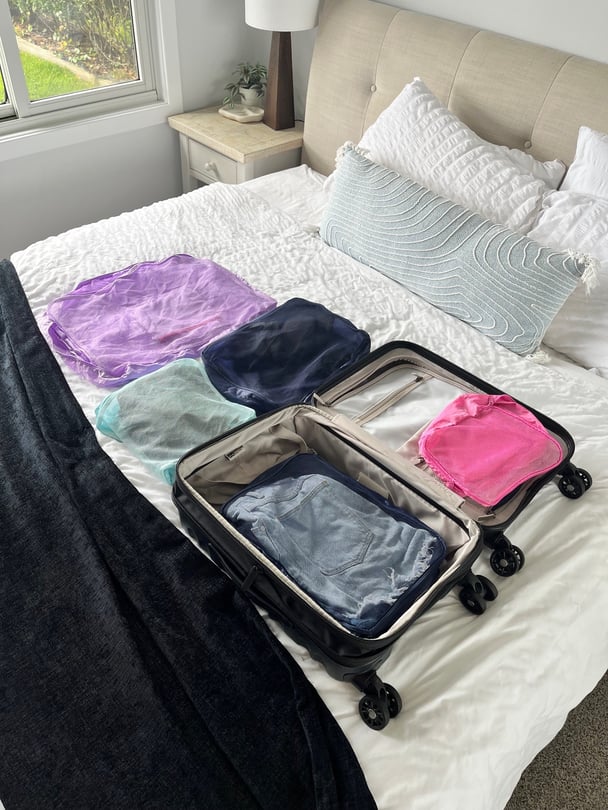 Colour-coded packing cubes of clothes in a suitcase.