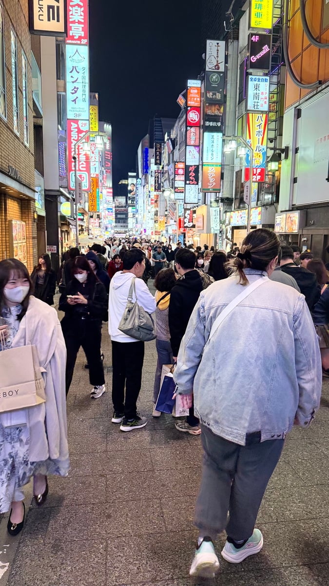 The back of a woman walking through a busy street in Tokyo, Japan.