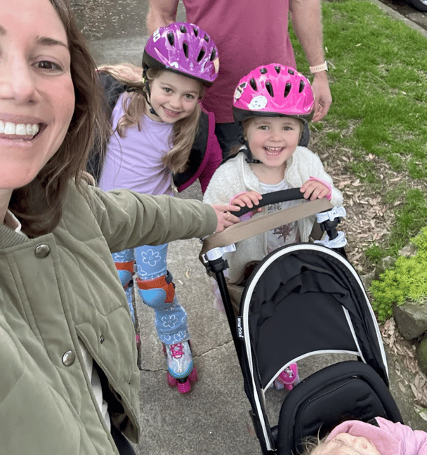 The writer Hannah smiling at the camera while taking a photo of her smiling family walking behind her.