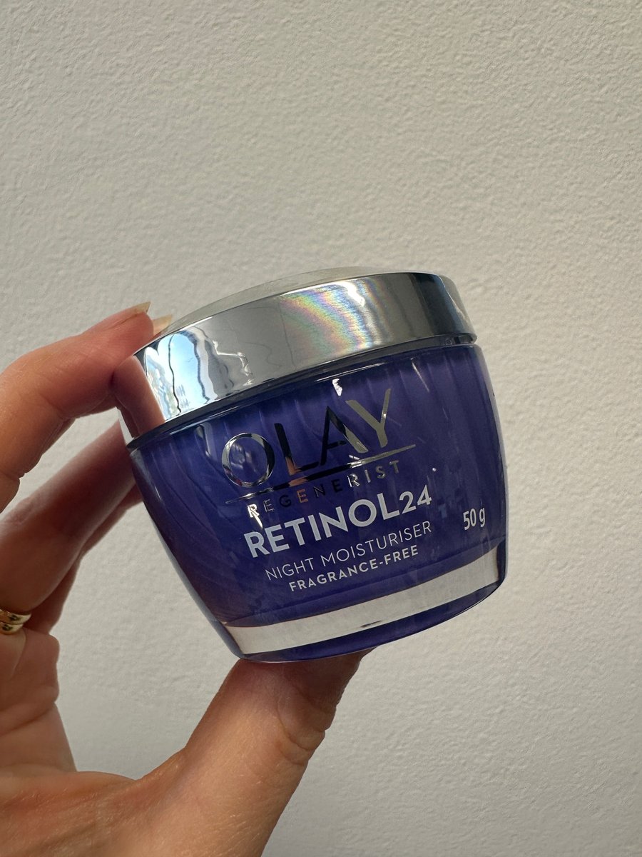 A hand holding a tub of Olay Retinol 24 Night Moisturiser.