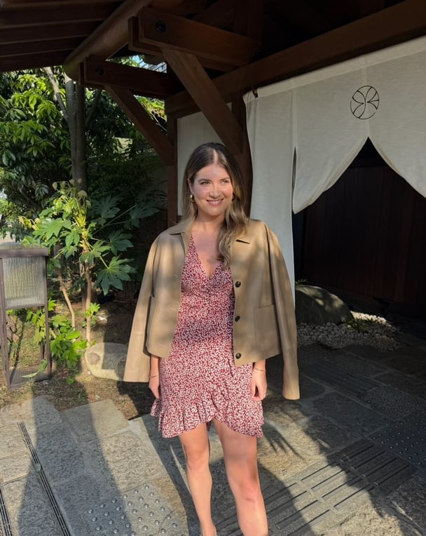 Paige wears a red wrap dress with a tan jacket.
