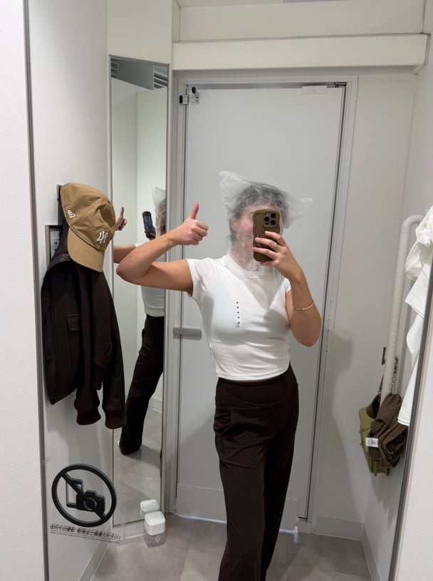 Paige in a changeroom with a mesh bag over her head to protect her shirt.