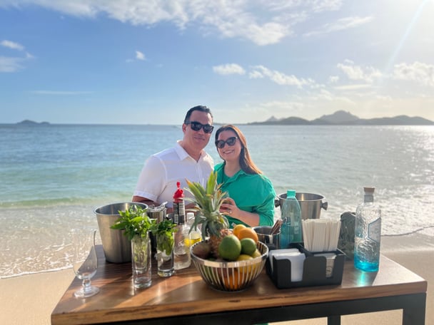 couple poses with cocktail making station on the beach
