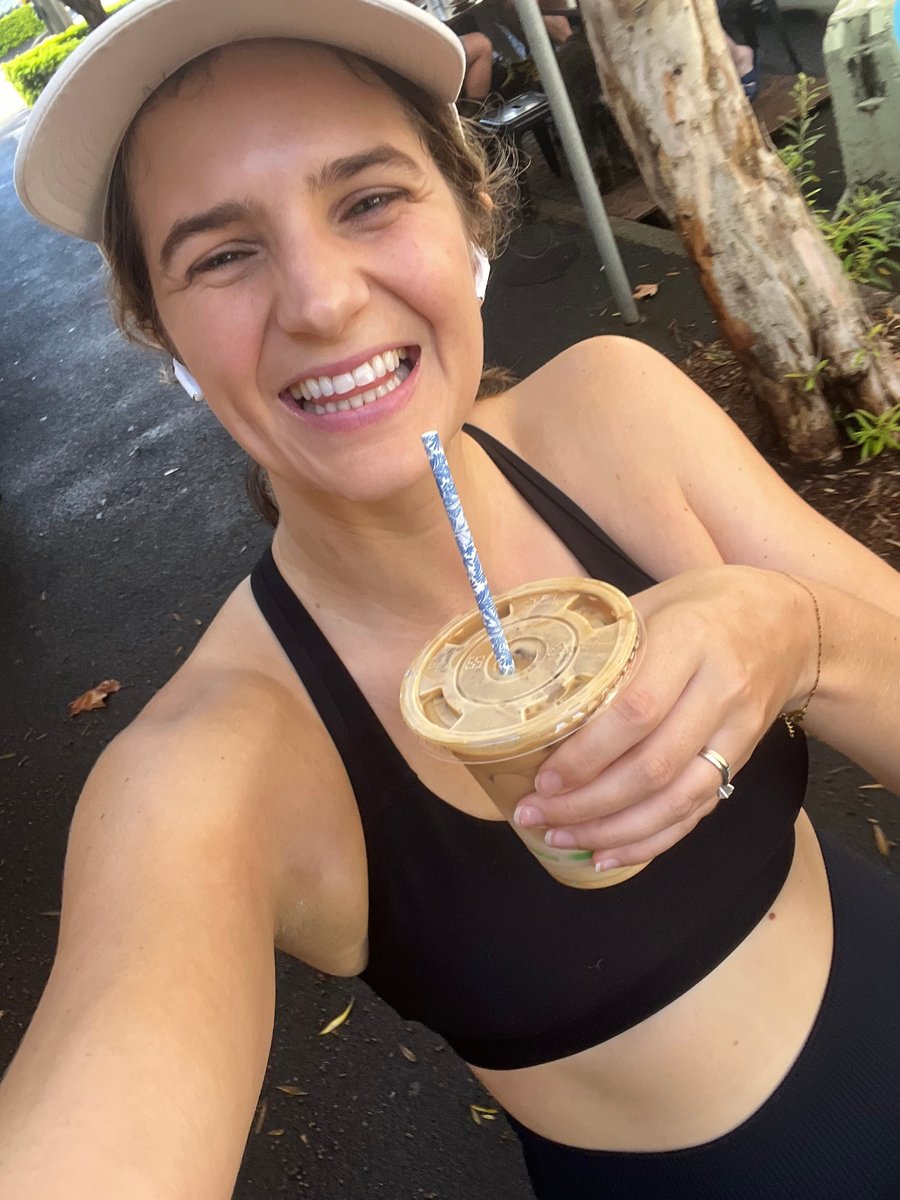 A woman takes a stroll in a workout set with an iced coffee in hand.