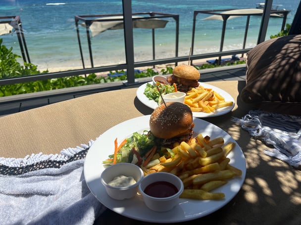 plates of burgers and chips against a beach background