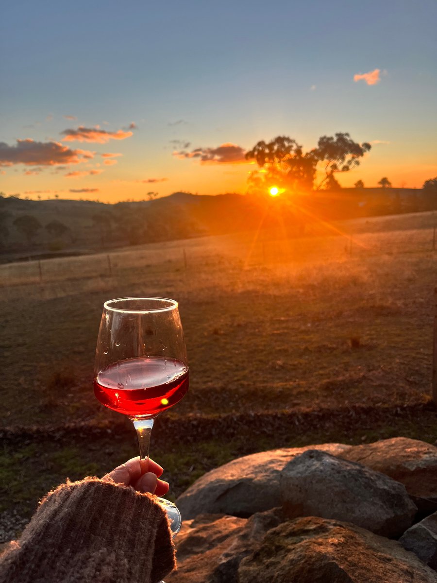 Relaxing farm holiday moment: red wine and sunset views over Mudgee countryside.