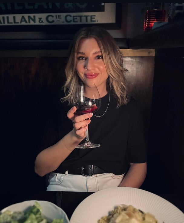 Rebecca sitting at a dinner table with a glass of red wine.