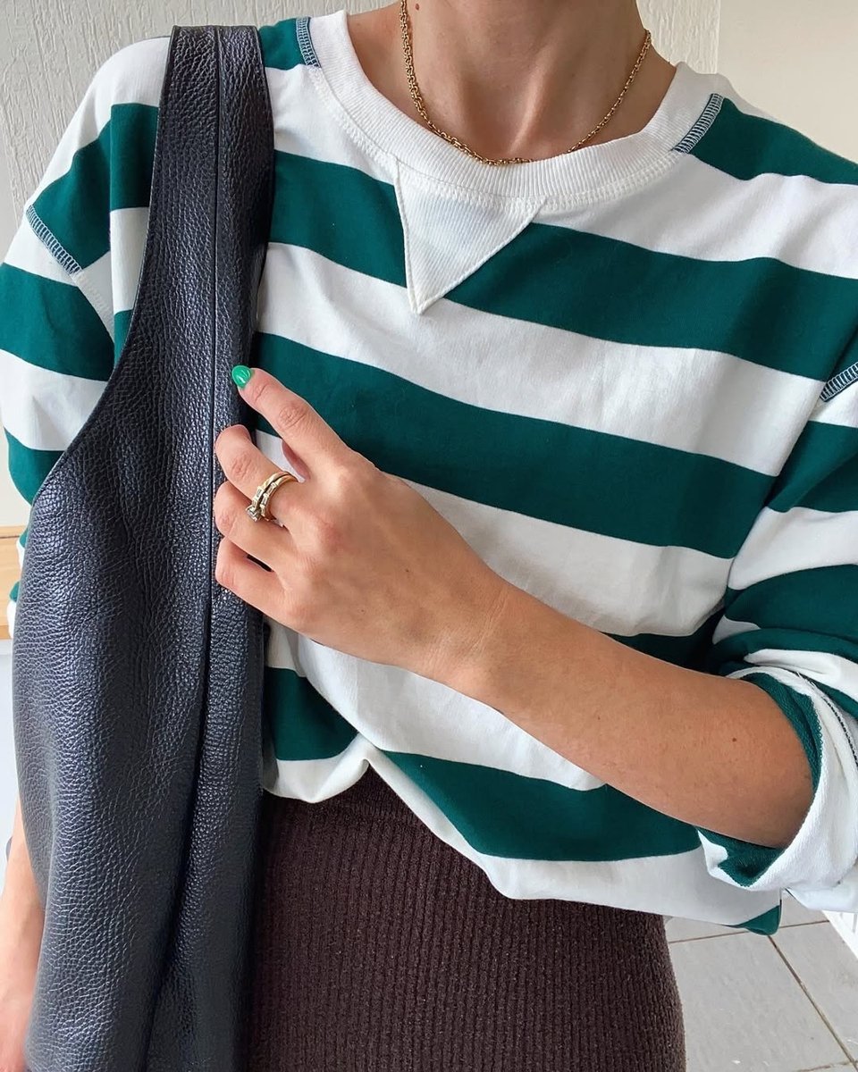 Wearing a striped green and white rugby jumper and black leather bag.