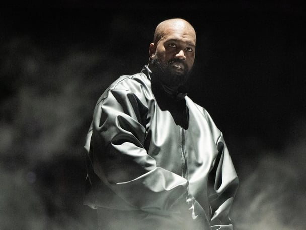 Rapper Kanye West wearing black jacket as he performs onstage during the