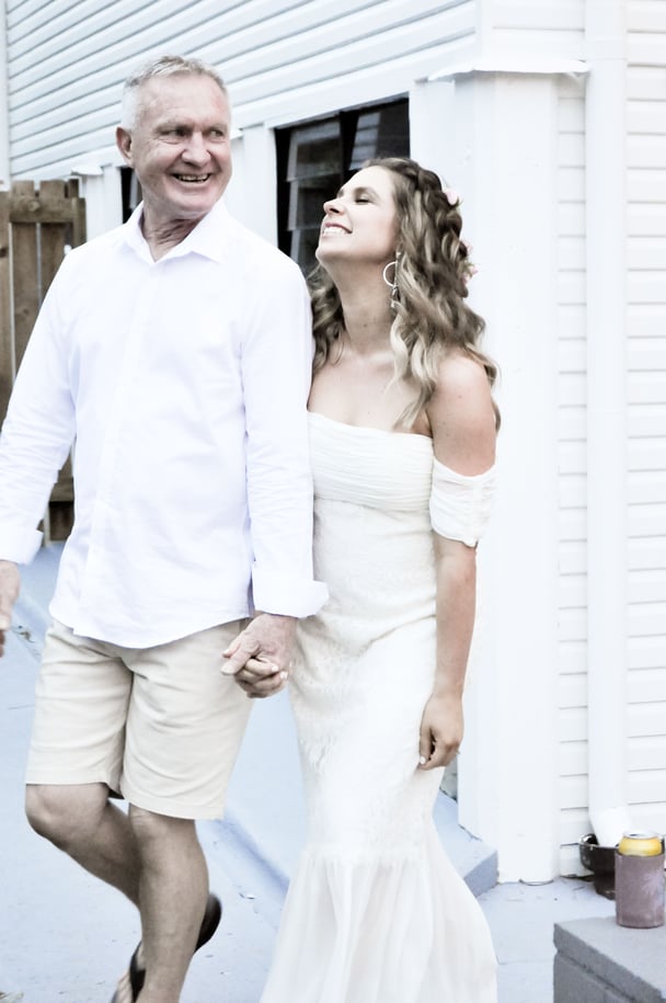 A father holding hands with his daughter on her wedding day. 