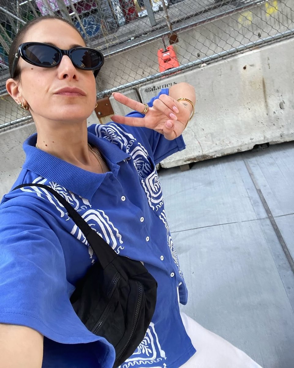 A woman wears a bright blue shirt and shows off her black nylon bumbag.