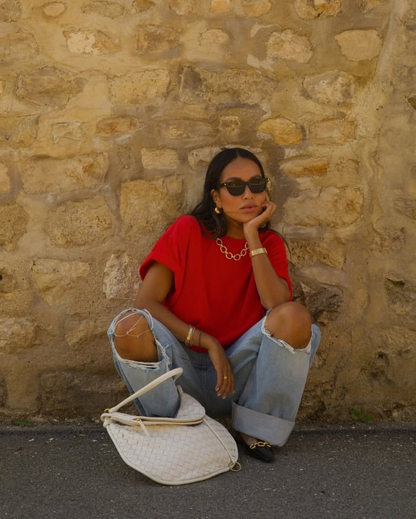 Julie Sarinara wears a cherry red oversized t-shirt and baggy blue jeans.