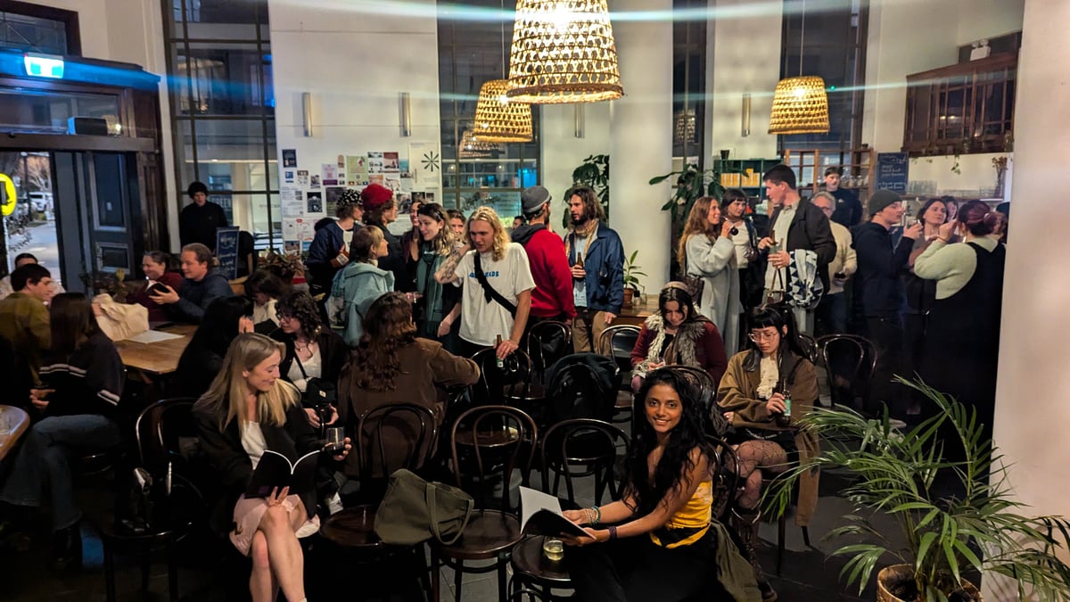 Group of people holding pamphlets and chatting.