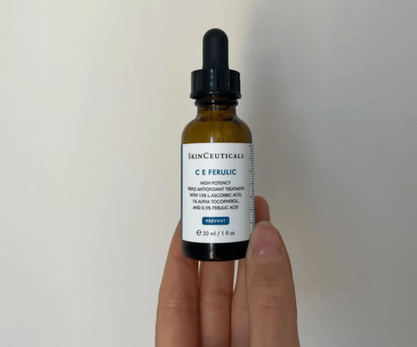 Woman's hand holding SkinCeuticals C E Ferulic Serum.